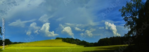 Scenic landscape with storm cloud in background over green agriculture fields,birch tree and meadows at spring daylight. Dramatic storm clouds and sky.Relaxing nature,sushine. Panoramic photo. Czech R © Jansk