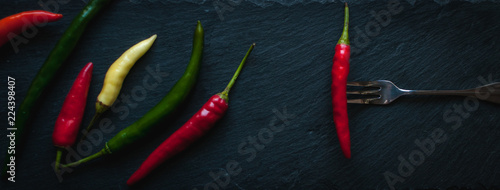 Mix of chili peppers on dark background, top view