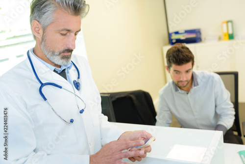 doctor consulting his phone during consultation with a patient