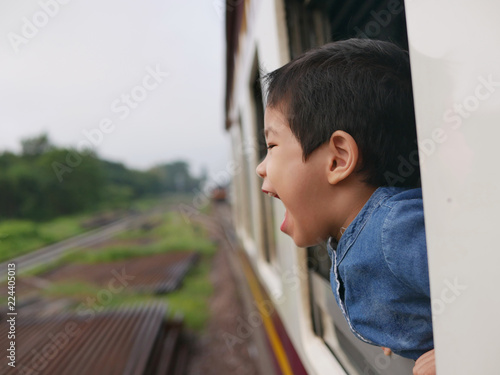 Little Asian baby girl, 32 months old, enjoys sticking her head out of a train window and having the wind whips against her face