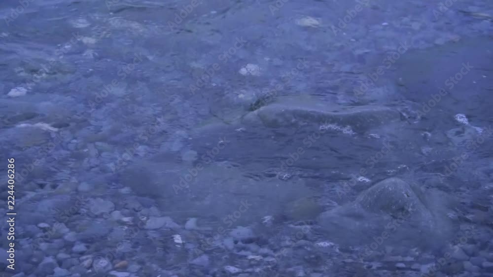 Waves are washing on stones and pebbles on the shore 2. Slow motion.
