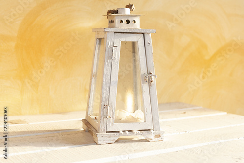 White wooden lantern with flame, on yellow background