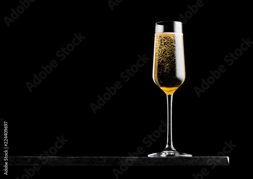 Elegant glass of yellow champagne with bubbles on blavk marble board on black background. Space for text