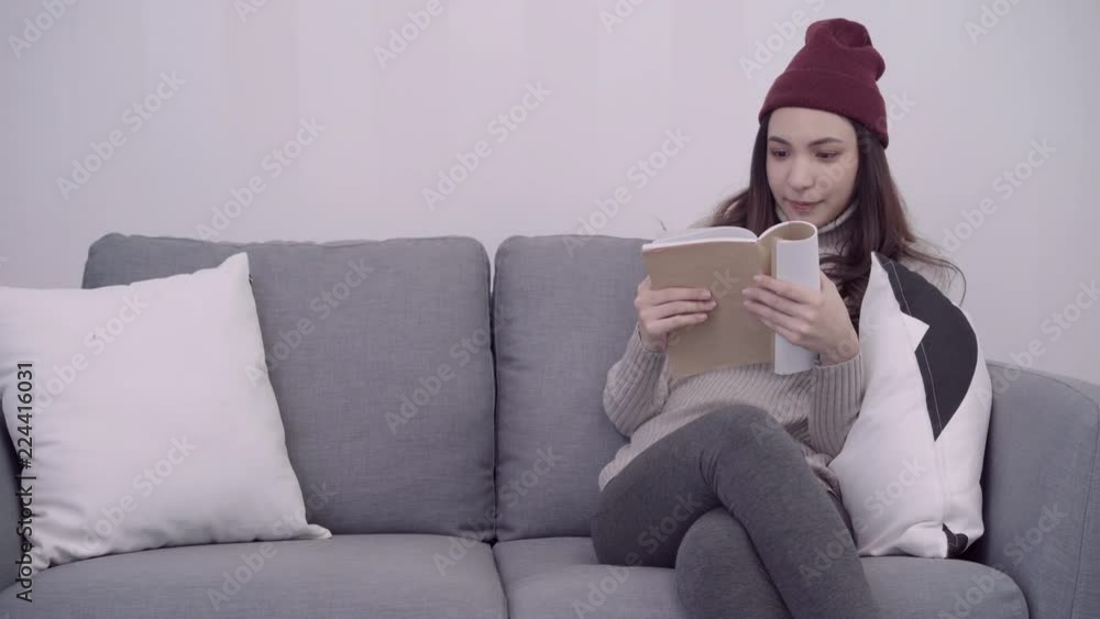 Portrait of beautiful attractive Asian woman reading a book while sitting on the sofa when relax in living room at home. Lifestyle women at home in Christmas and New year holidays concept. Portrait of beautiful attractive Asian woman reading a book while sitting on the sofa when relax in living room at home. Lifestyle women at home in Christmas and New year holidays concept.