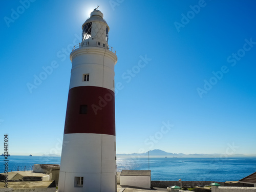 Lighthouse with a sunlight behind on beautiful blue sea and sky background. Gibraltar, Europa point