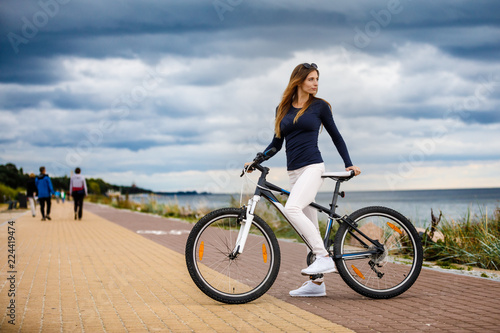 Fototapeta Naklejka Na Ścianę i Meble -  Young woman and bike at seaside