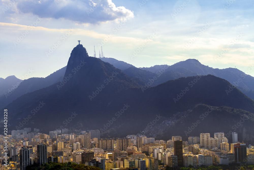Christ the Redeemer statue on Corcovado hill with Botafogo neighborhood below during sunset in Rio de Janeiro, Brazil