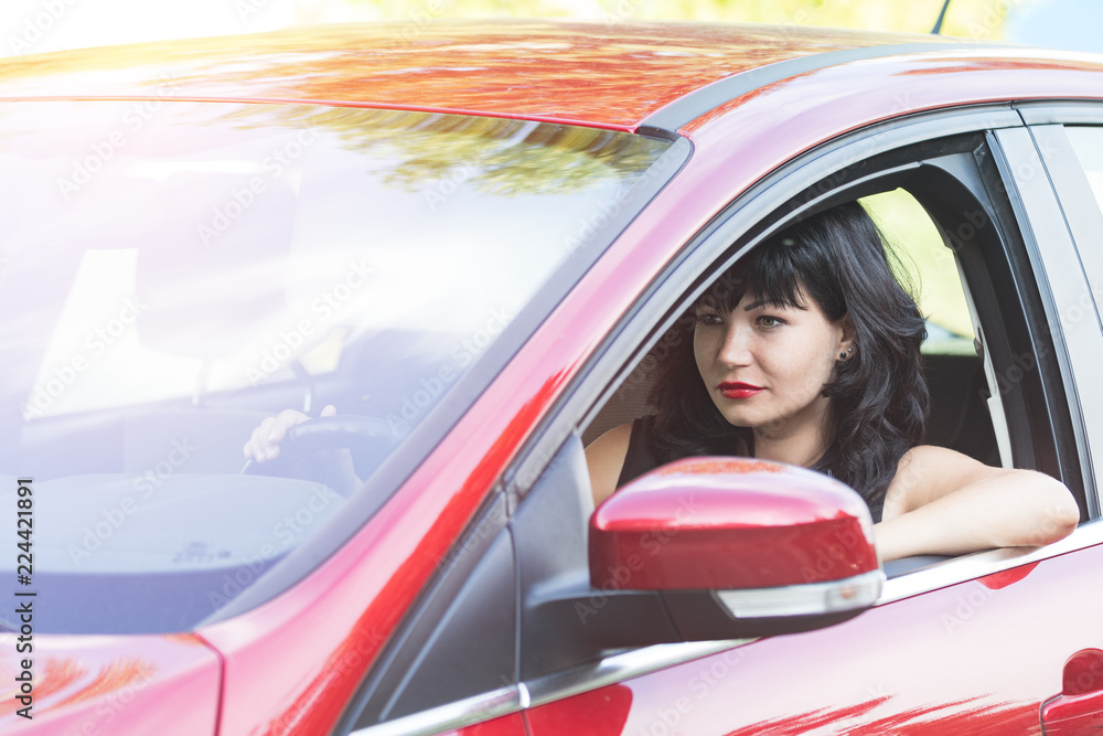 Sexy beautiful pretty brunette with red lipstick in the red car