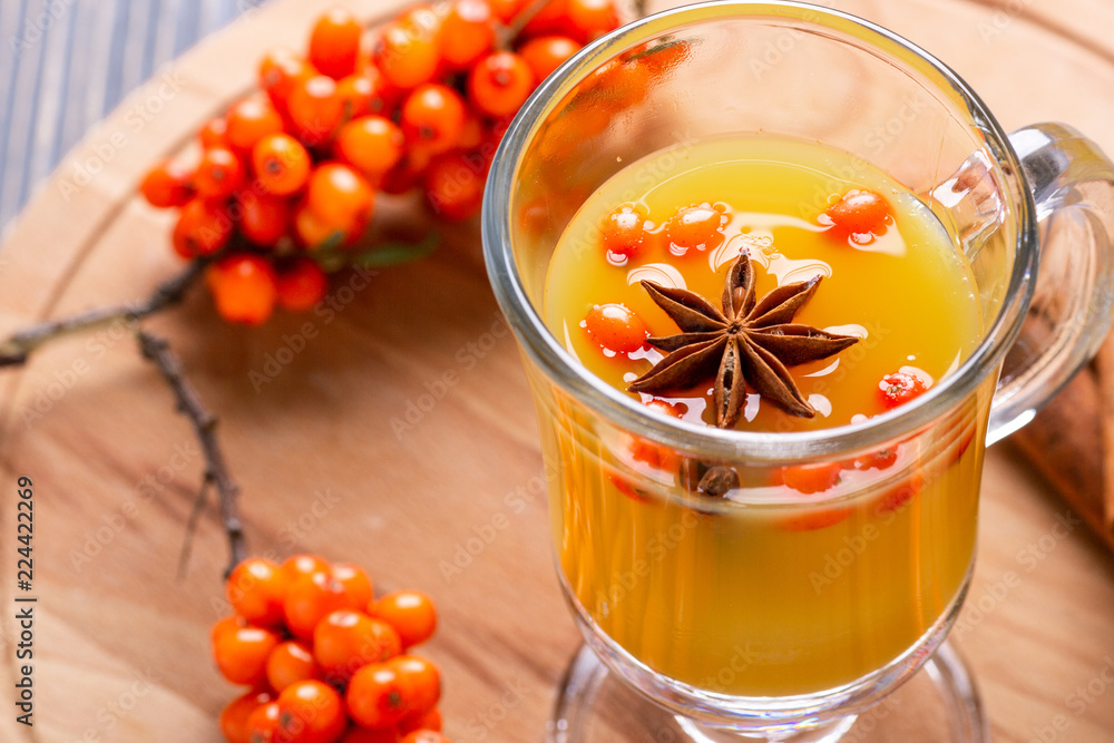 Hot beverage of sea-buckthorn berries in glass cup on wooden background. Rustic style. Hot beverage of sea-buckthorn berries in glass cup on wooden background. Rustic style.