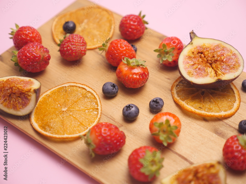 Fresh fruits on wooden plate. Fruit p;ate with strawberry, blueberry, sweet cherry on wooden background. Flat lay, top view. Assortment of juicy fruits on wooden table, on bright background.