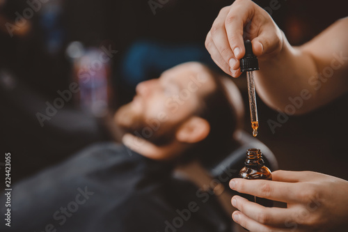 Oil for care and growth of beard, in background man.