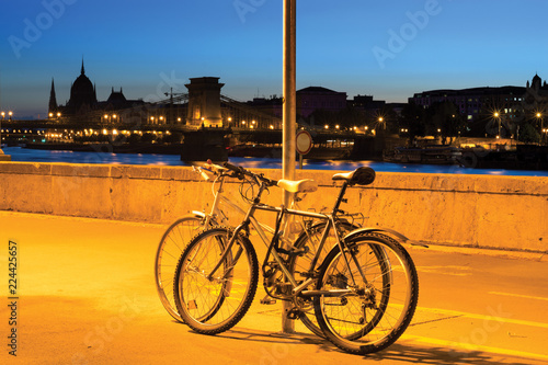 Two bicycles leaned to pile against night Budapest skyline