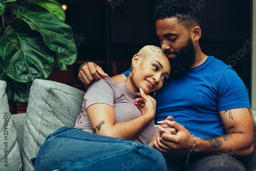 Young couple embracing each other while sitting on sofa