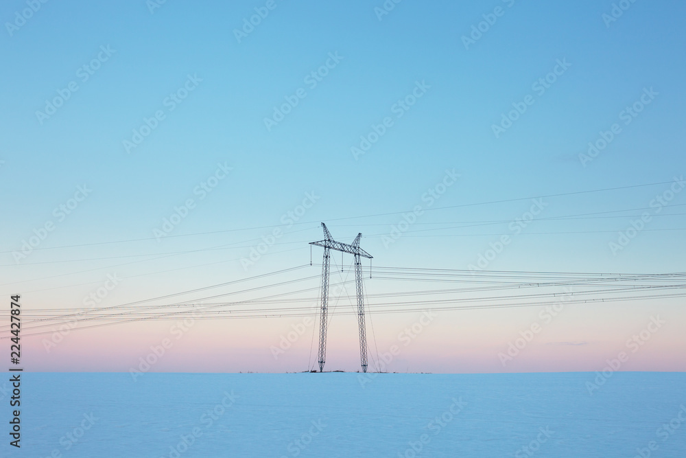 Power lines in snow field at pastel sunset