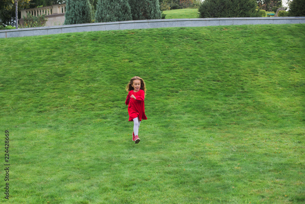 A little girl is running in the park.