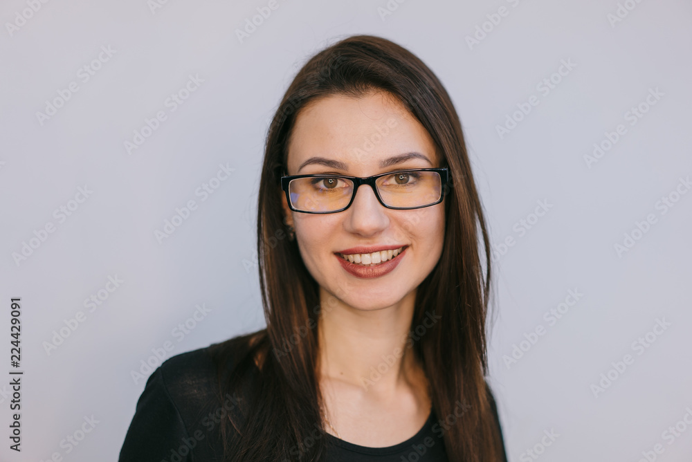 Fototapeta premium smiling young brunette with glasses on a white background. Close-up