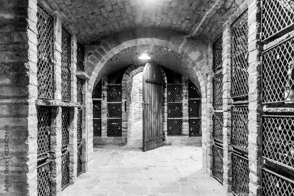 Old wine cellar with wine storage cases and open vintage wooden doors. Black and white image.