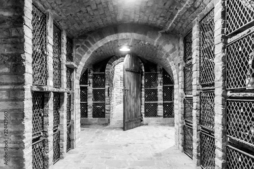 Old wine cellar with wine storage cases and open vintage wooden doors. Black and white image.