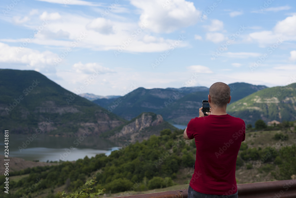 Fototapeta premium Young Man Taking Pictures With Mobile Smartphone Of Mountain and Landscape
