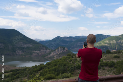 Young Man Taking Pictures With Mobile Smartphone Of Mountain and Landscape