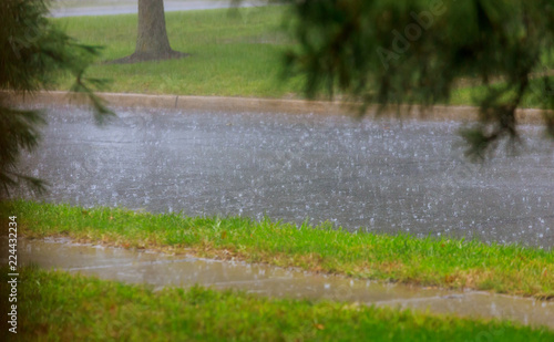 city road flooded during heavy rain. raindrops on water puddles. bad weather