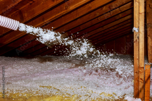 Worker Spraying mineral rock wool of house attic insulation photo