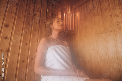 Foto Woman sitting in a wooden sauna spa taking steam bath