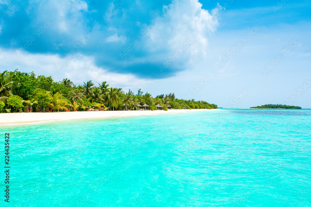 Beautiful sandy beach with sunbeds and umbrellas in Indian ocean, Maldives island