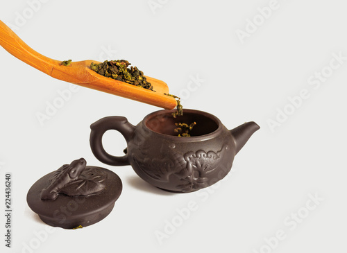 dry leaves of tea tieguanyin, scattered around a porcelain teapot, a tea blade. photo