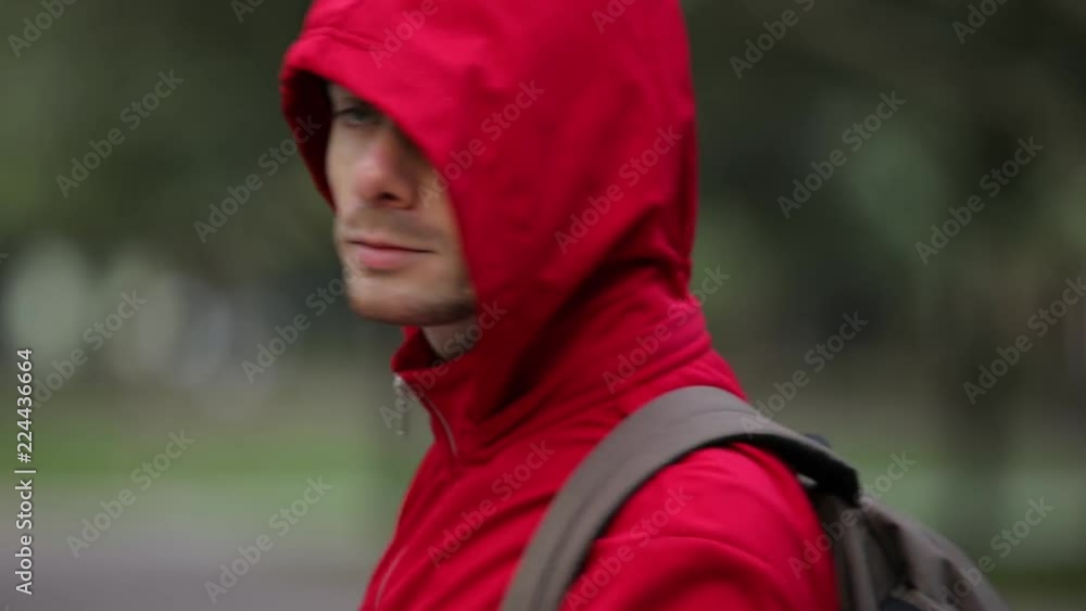 Rear view of man in red hood turn face and go away in park Rear view of man in red hood turn face and go away in park