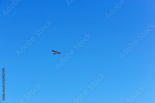 A small aircraft soars in the blue sky. Glider in the sky.