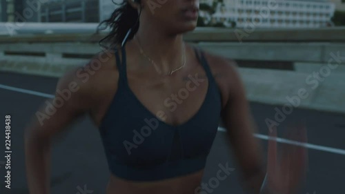 fit mixed race woman running on urban city road at sunrise training intense cardio endurance workout female runner athlete wearing earphones