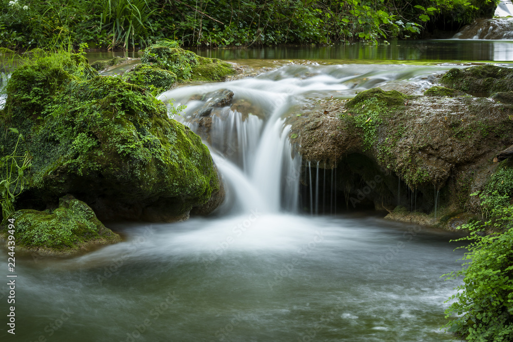 Small waterfall flowing on rock in woods in long exposure Small waterfall flowing on rock in woods in long exposure