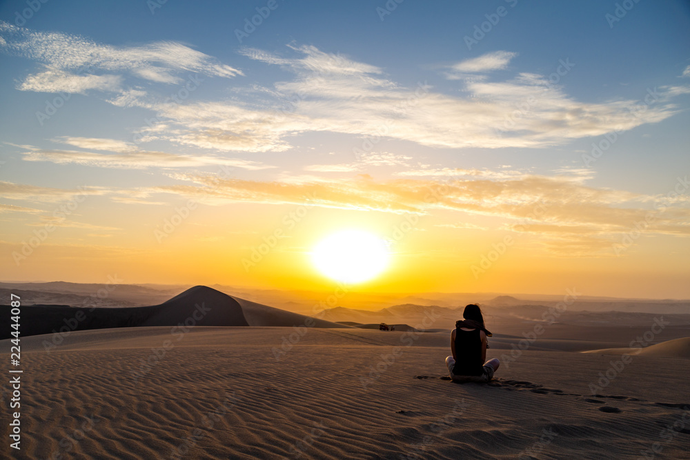 Femme assise qui regarde le Coucher du soleil dans le désert Huacachina Ica au Pérou Voyageuse aventurière paysage