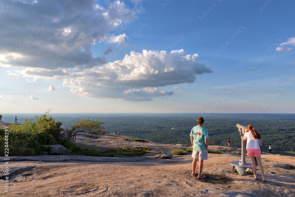 Unidentifiable people viewing the sights of the green trees from the top of Stone Mountain in Georgia using the viewing device