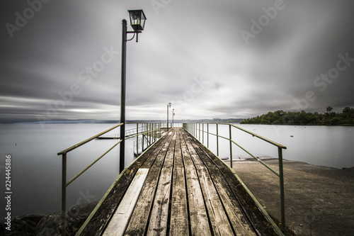 A dramatic view in of a pier going to the infinity at Lakes Region in Chile, just amazing seeing how deep we can go in the horizon on this wooden dock with its lamps. Rupanco Lake, Chile photo