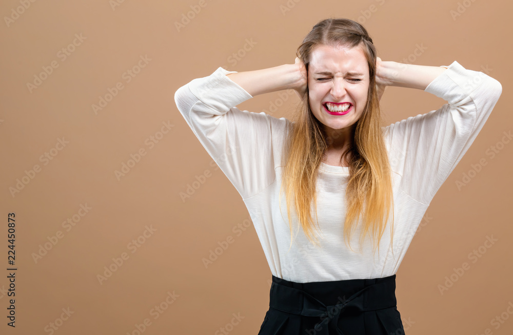 Young woman blocking her ears on a brown background Young woman blocking her ears on a brown background