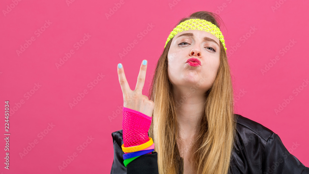 Woman in 1980's fashion giving the peace sign on a pink background Woman in 1980's fashion giving the peace sign on a pink background