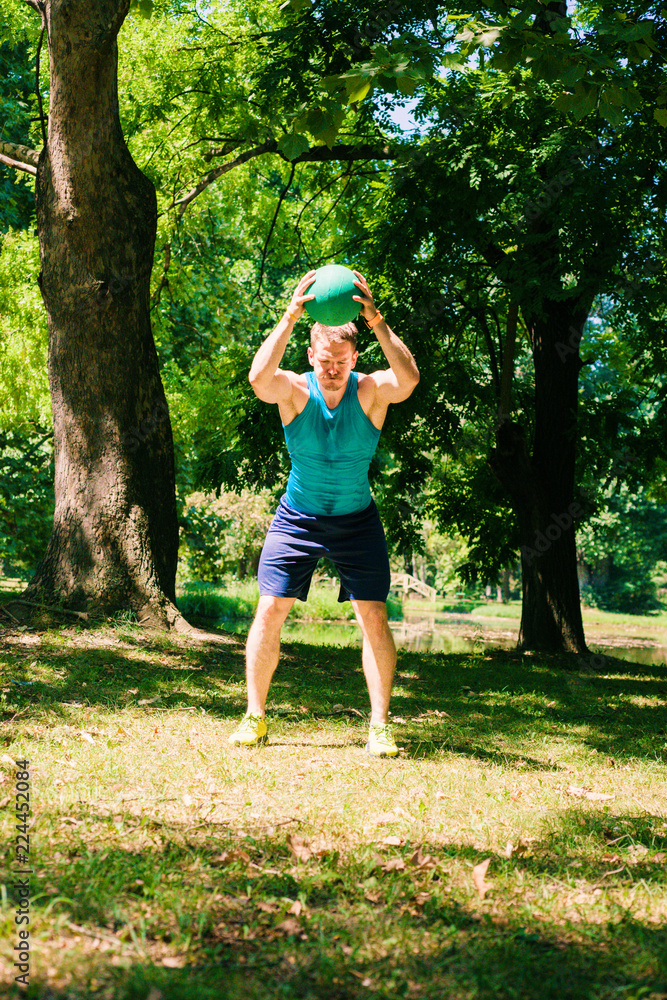 Fototapeta premium Active and muscular man keeping fit by exercising using a medecine ball
