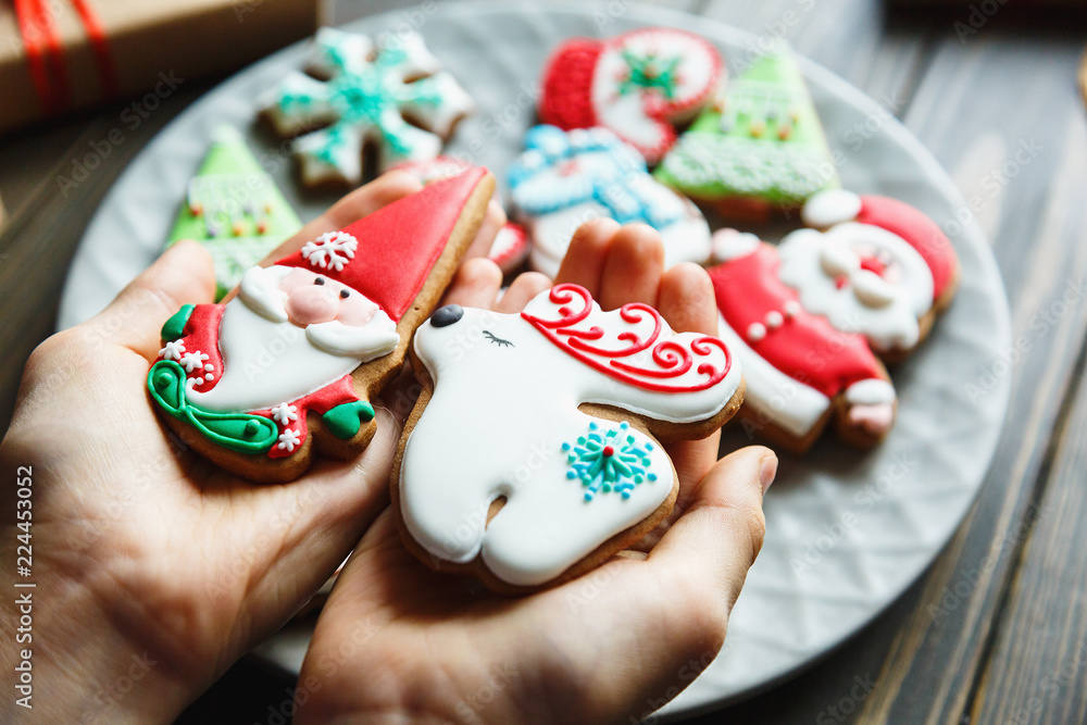 Gingerbread cookies for christmas, new year in kids hands on the wooden table. Festive, sweet pastry, delicious biscuits. Home celebration, decoration concept