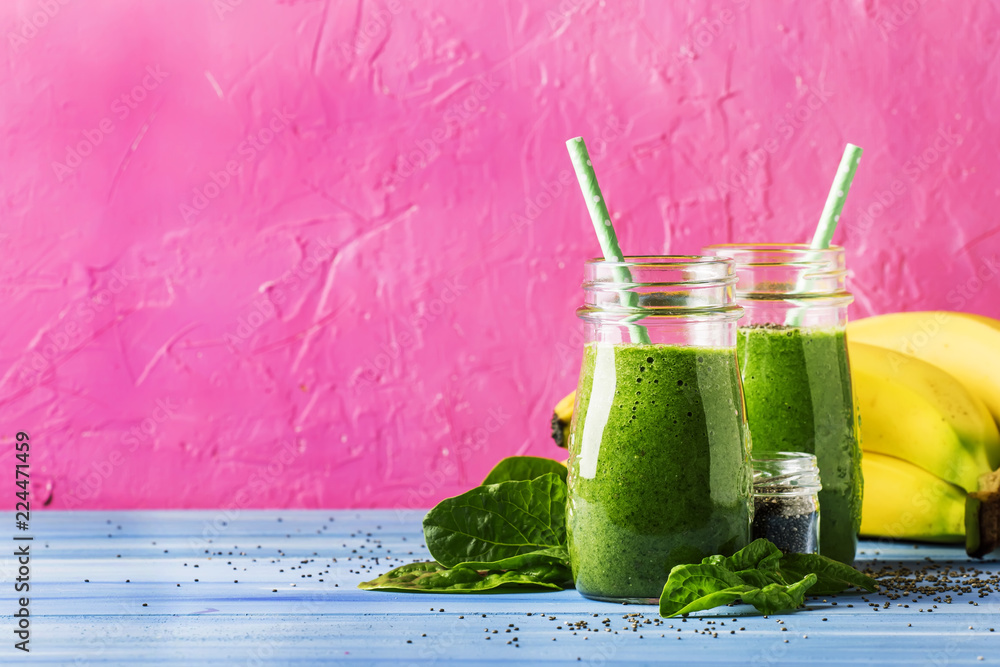 Green smoothies in glass bottles on cool pink blue background with yellow bananas, selective focus - obrazy, fototapety, plakaty 