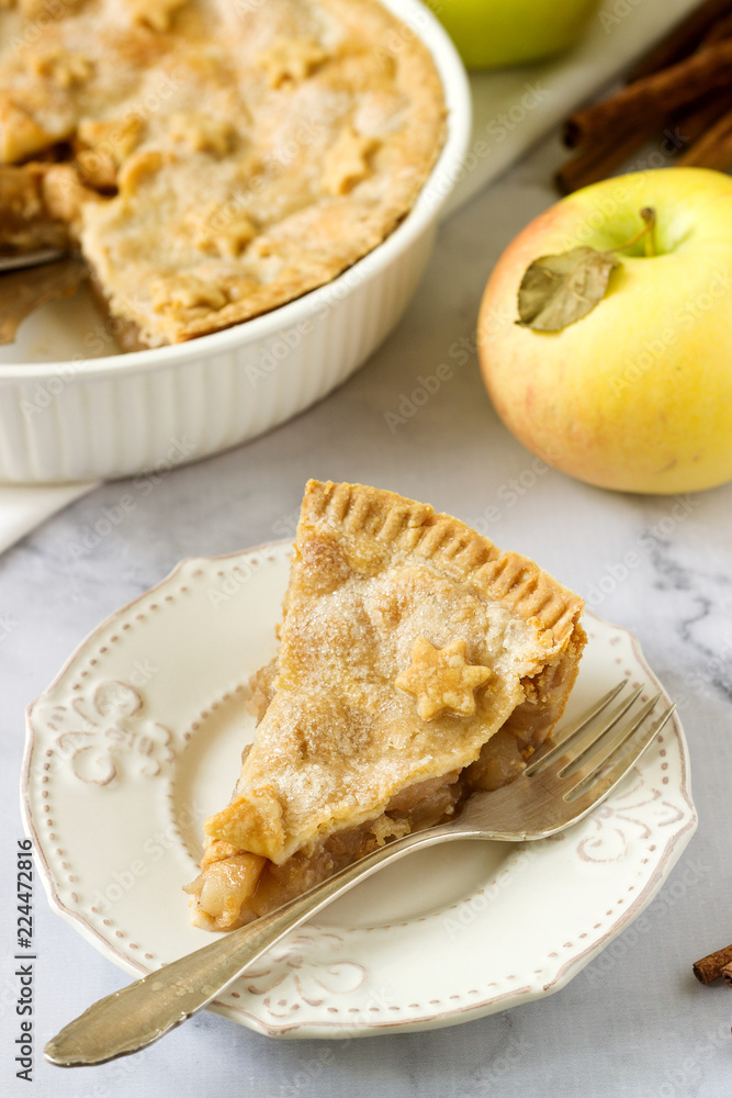 A traditional American apple pie decorated with stars and sugar, apples and cinnamon on a light background. A traditional American apple pie decorated with stars and sugar, apples and cinnamon on a light background.