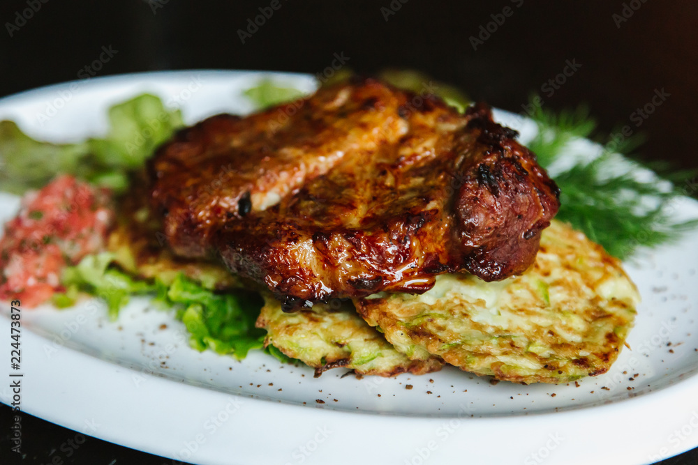 Pork steak with mushrooms, tomatoes, cucumbers, pepper, sauce on a black background