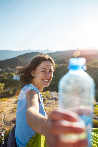 A woman holds out a bottle of water.