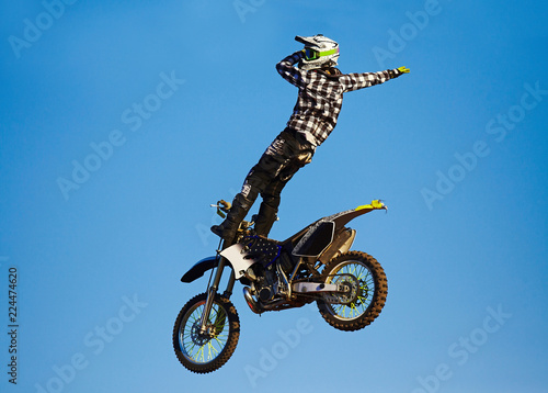 Pro motocross rider riding fmx motorbike, jumping performing extreme stunt. Professional biker jumps
