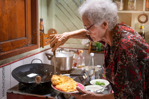 Senior asian woman cooking omelet in kitchen at home,lifestyle of asian old woman concept