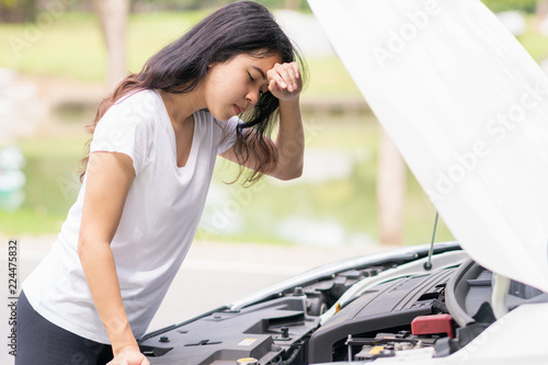 Woman looking at a broken car engine. © amornchaijj