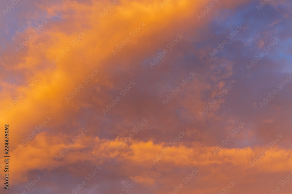 Abstract background with a texture of clouds at sunset similar to a fire. Heavenly landscape. A beautiful morning blue sky painted in the sun in bright red and orange colors