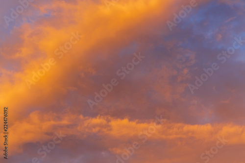 Abstract background with a texture of clouds at sunset similar to a fire. Heavenly landscape. A beautiful morning blue sky painted in the sun in bright red and orange colors