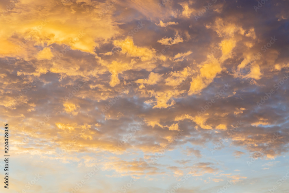 Abstract background with a texture of clouds at sunset. Heavenly landscape. Beautiful morning blue sky painted in the sun in bright yellow and orange colors